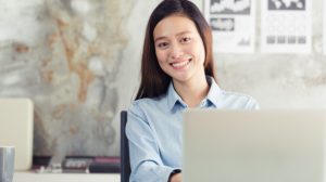asian-women-sitting-smiling-while-working-on-mobile-office converged solutions
